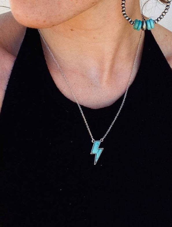 Necklace with a turquoise pendant worn by a person against a black background