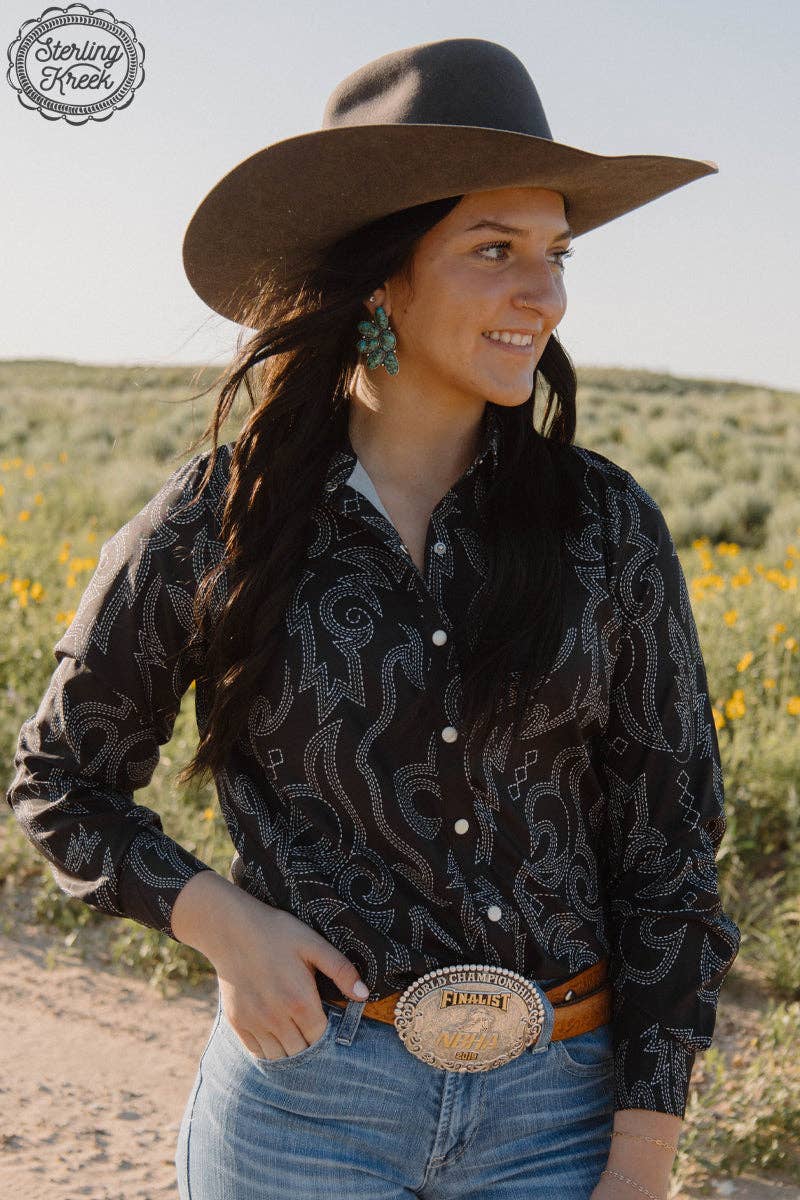 Woman wearing a cowboy hat and patterned shirt in a desert setting