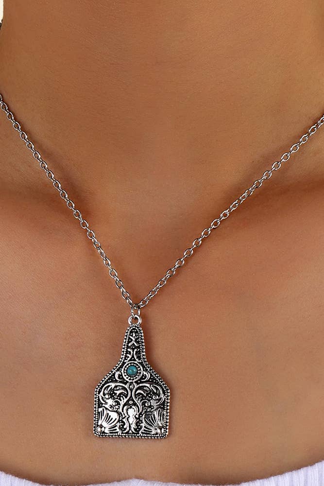 Silver necklace with a detailed pendant on a person's neck