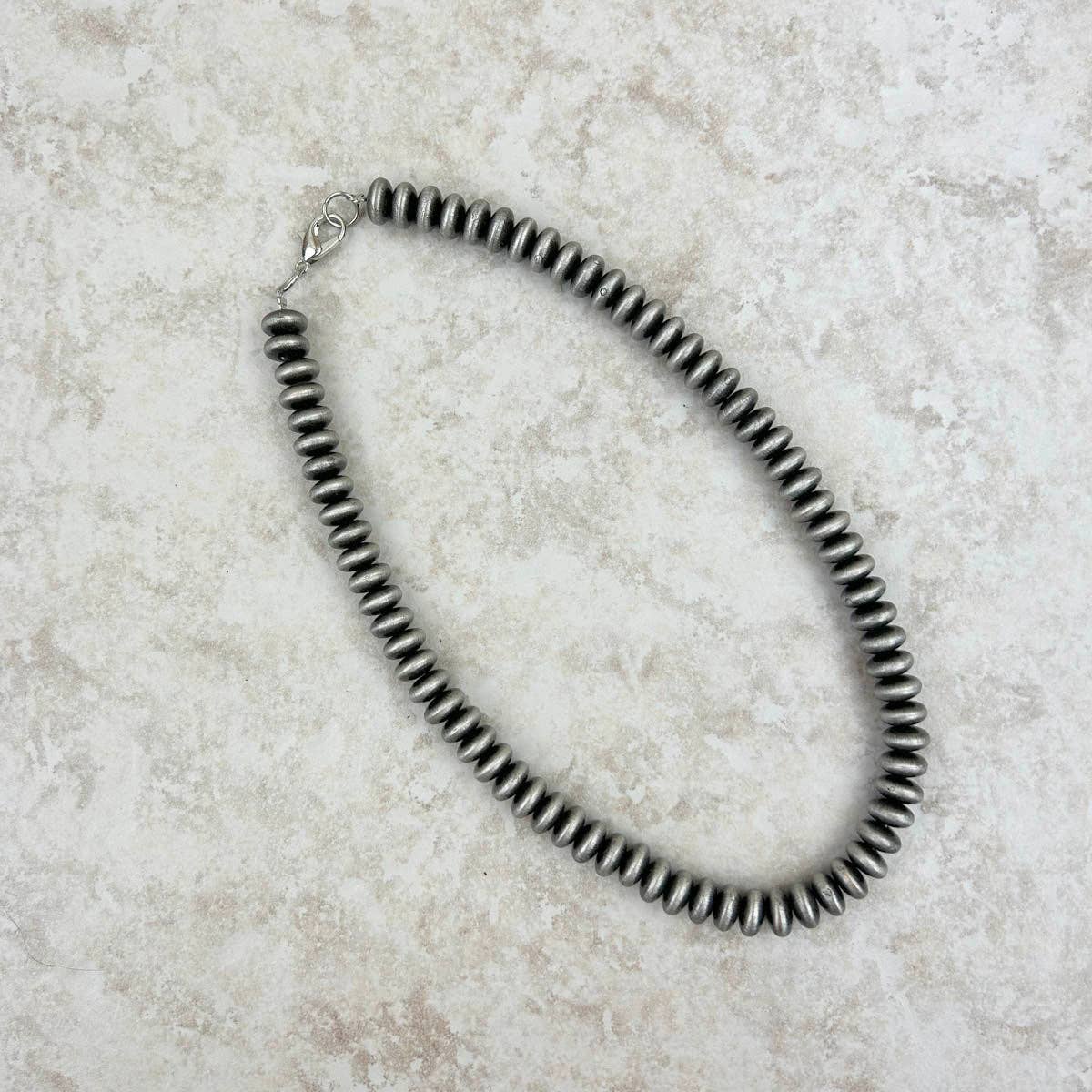 Necklace with black beads on a light stone surface