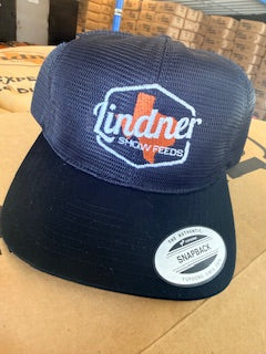 Navy blue cap with 'Lindner Show Feeds' logo on a cardboard box background