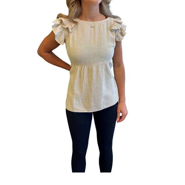 A woman wearing a cream-colored textured top with ruffled cap sleeves and dark navy leggings, shown against a plain white background.