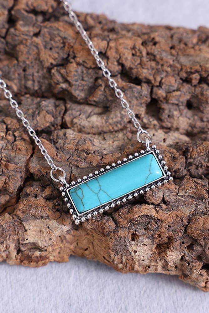 Turquoise stone necklace on a textured wooden surface