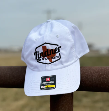 White cap with logos on a wooden post against a blurred background