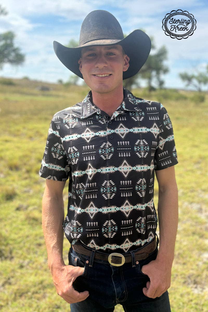 Man wearing a black patterned shirt and cowboy hat in an outdoor setting