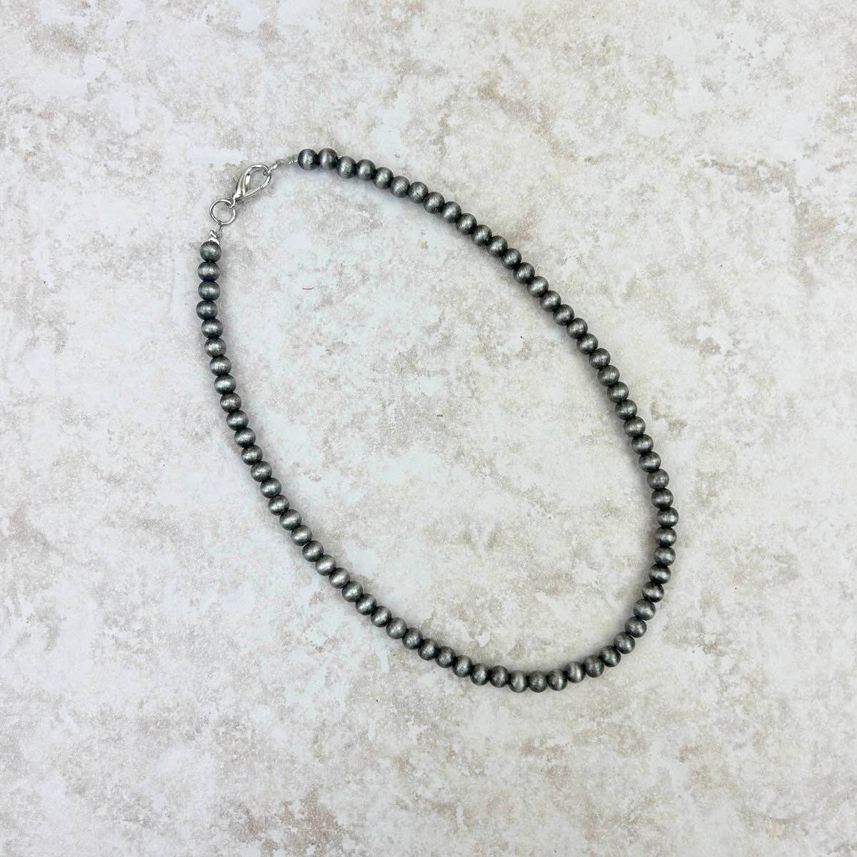 Black beaded necklace on a light stone surface