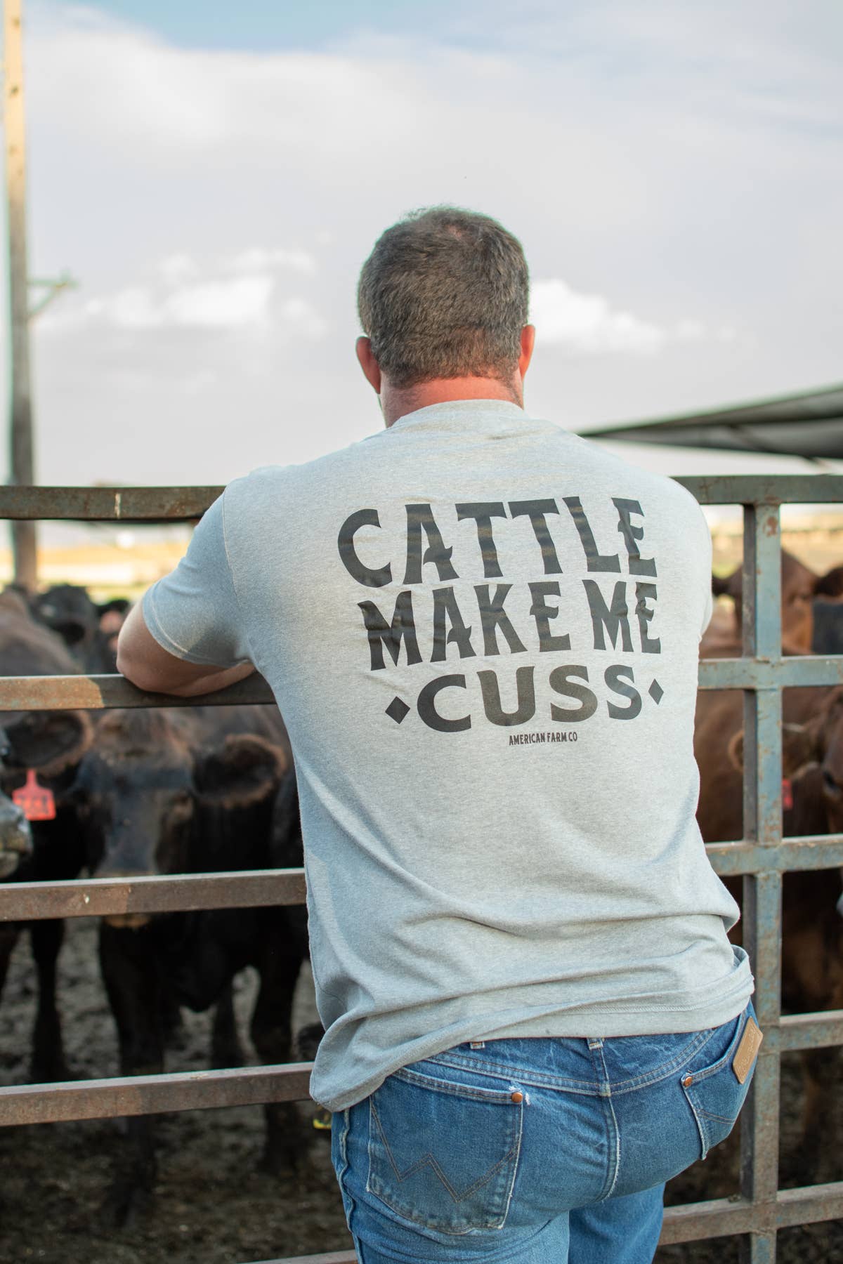 Man wearing a t-shirt with 'Cattle Make Me Cu$$' text in a cattle pen.