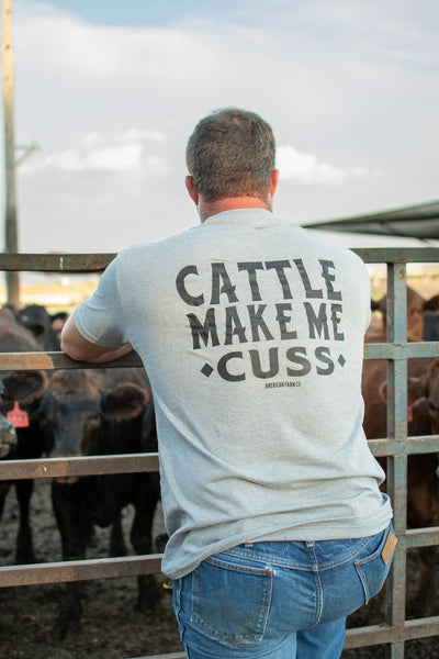 Man wearing a t-shirt with 'Cattle Make Me Cu$$' text in a cattle pen.