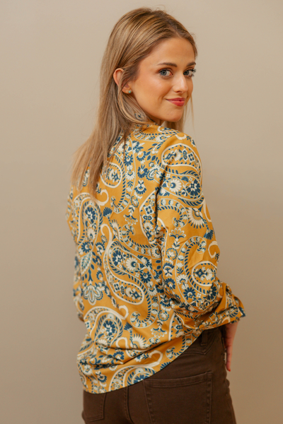 Woman wearing a patterned blouse against a beige background