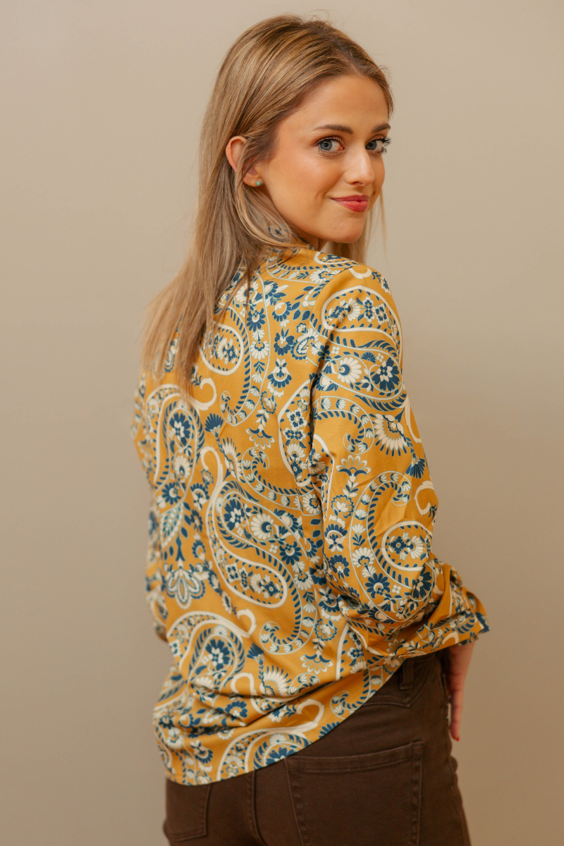 Woman wearing a patterned blouse against a beige background