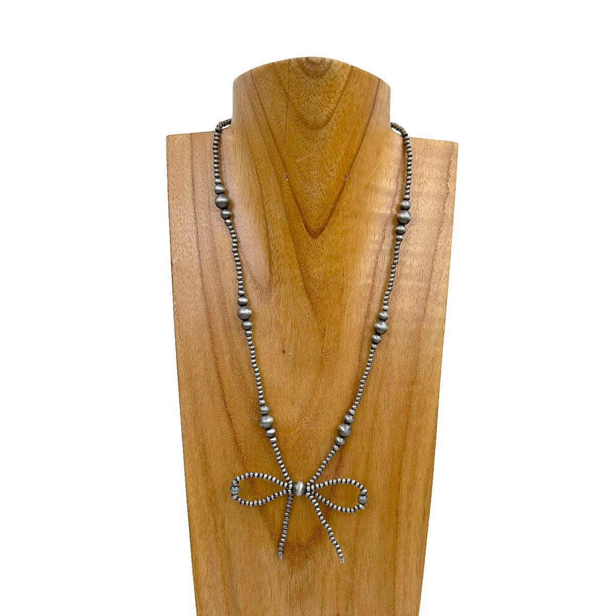 Silver beaded necklace with a bow pendant on a wooden stand.