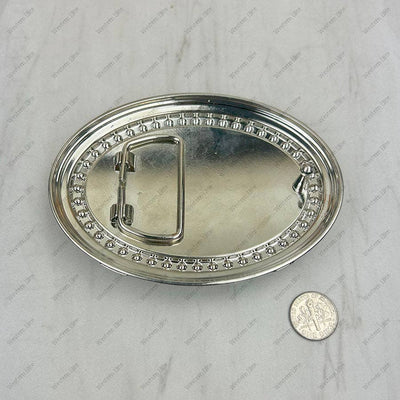 Silver belt buckle on a light gray background with a coin for scale