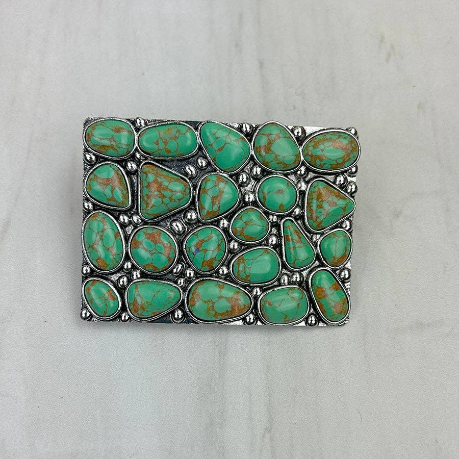 Belt buckle with turquoise stones on a light gray background