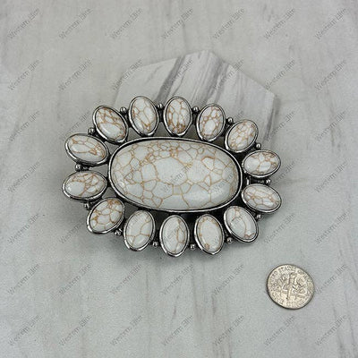 Decorative stone with silver frame on a marble surface, next to a coin for scale.