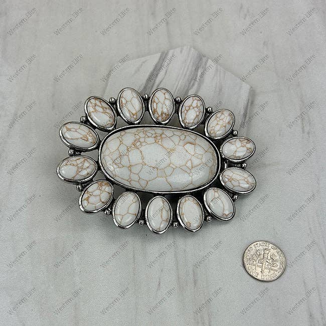 Decorative stone with silver frame on a marble surface, next to a coin for scale.