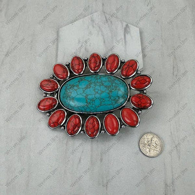 Brooch with red stones and turquoise center on a gray background