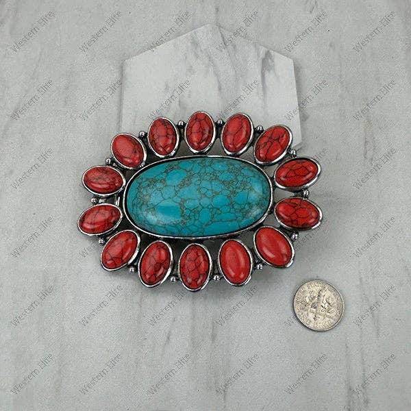 Brooch with red stones and turquoise center on a gray background