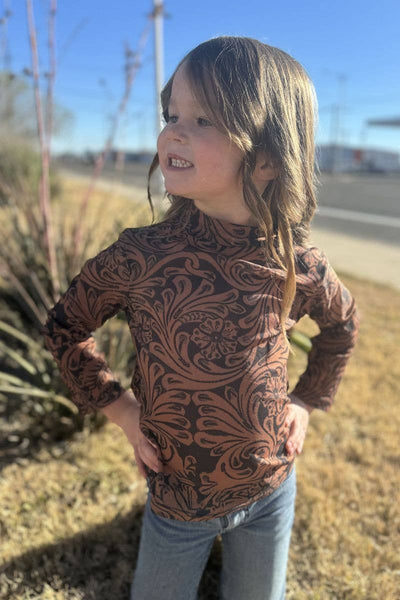 Child wearing a patterned long-sleeve shirt outdoors on a sunny day