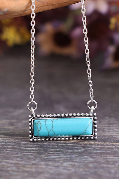 Turquoise stone necklace with silver chain on a wooden surface