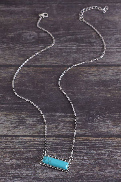 Silver necklace with a turquoise pendant on a wooden surface