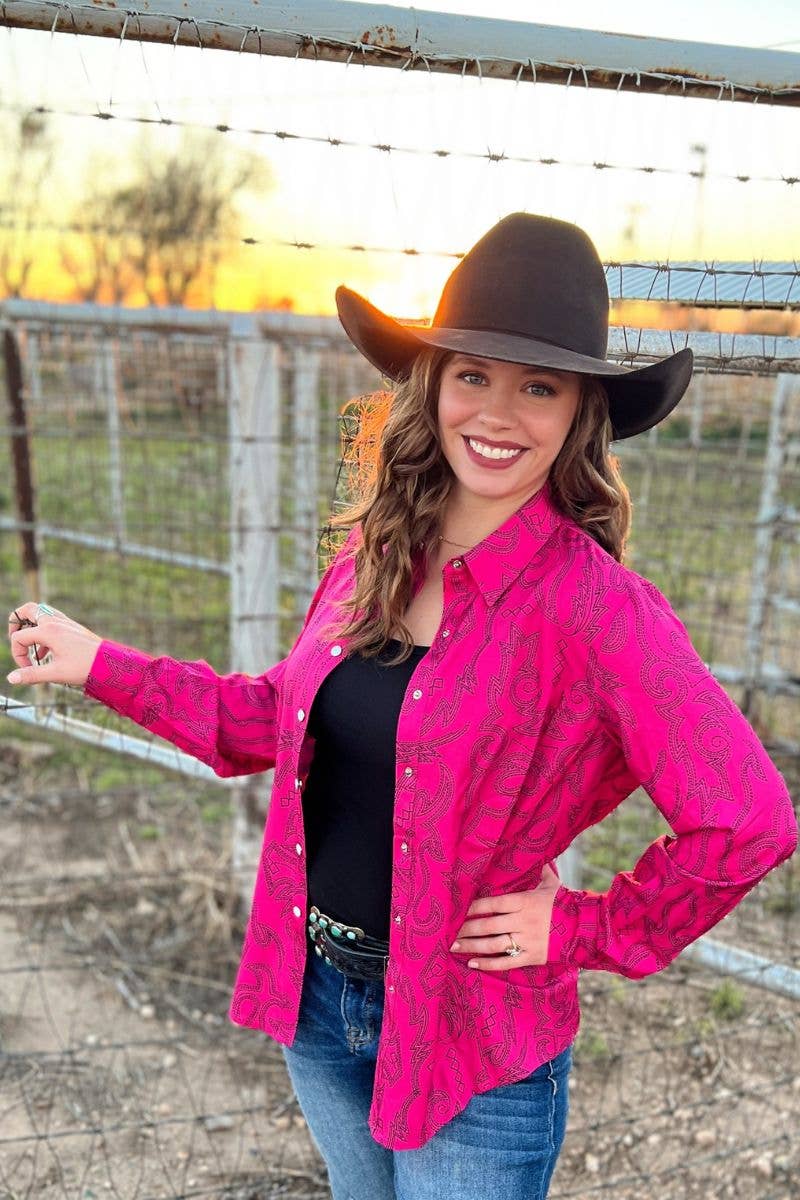 Woman wearing a pink cowboy shirt and brown hat in front of a sunset.