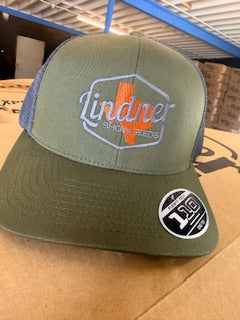 Green and blue cap with 'Lindner' logo on a cardboard surface