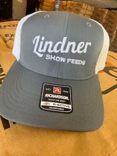 Gray cap with 'Lindner Show Feeds' branding on a wooden surface