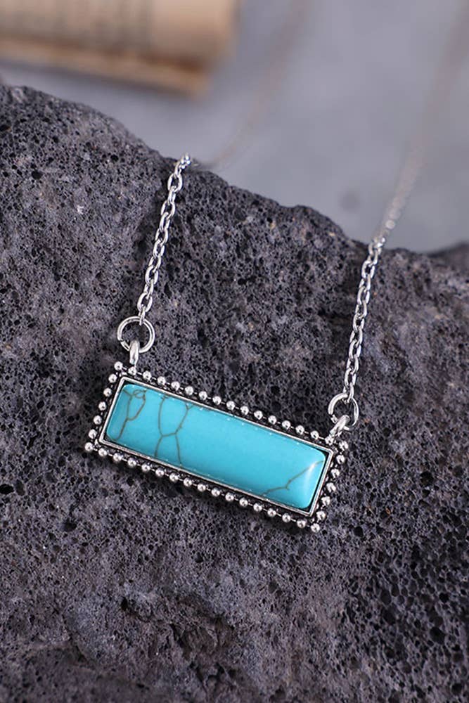 Turquoise pendant necklace on a dark stone surface