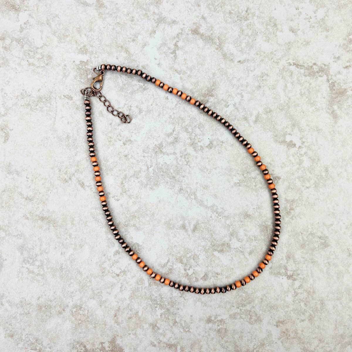 Necklace with orange and brown beads on a light stone surface