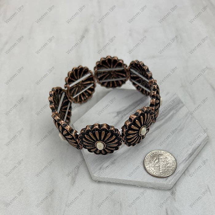Bronze floral bracelet on a marble stand with a coin for scale