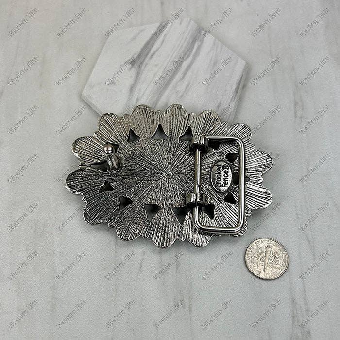 Silver floral-patterned belt buckle on a marble surface with a coin for scale.