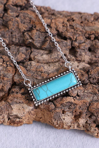 Turquoise stone necklace on a textured wooden surface