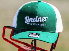 Green and white cap with 'Lindner Show Feeds' logo on a blurred background