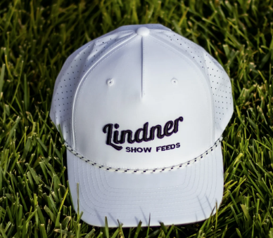 White cap with 'Lindner Show Feeds' logo on grass