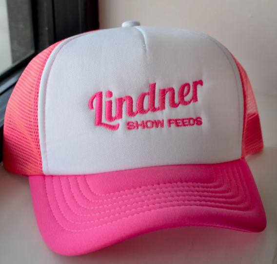 Pink and white cap with 'Lindner Show Feeds' text on a light background